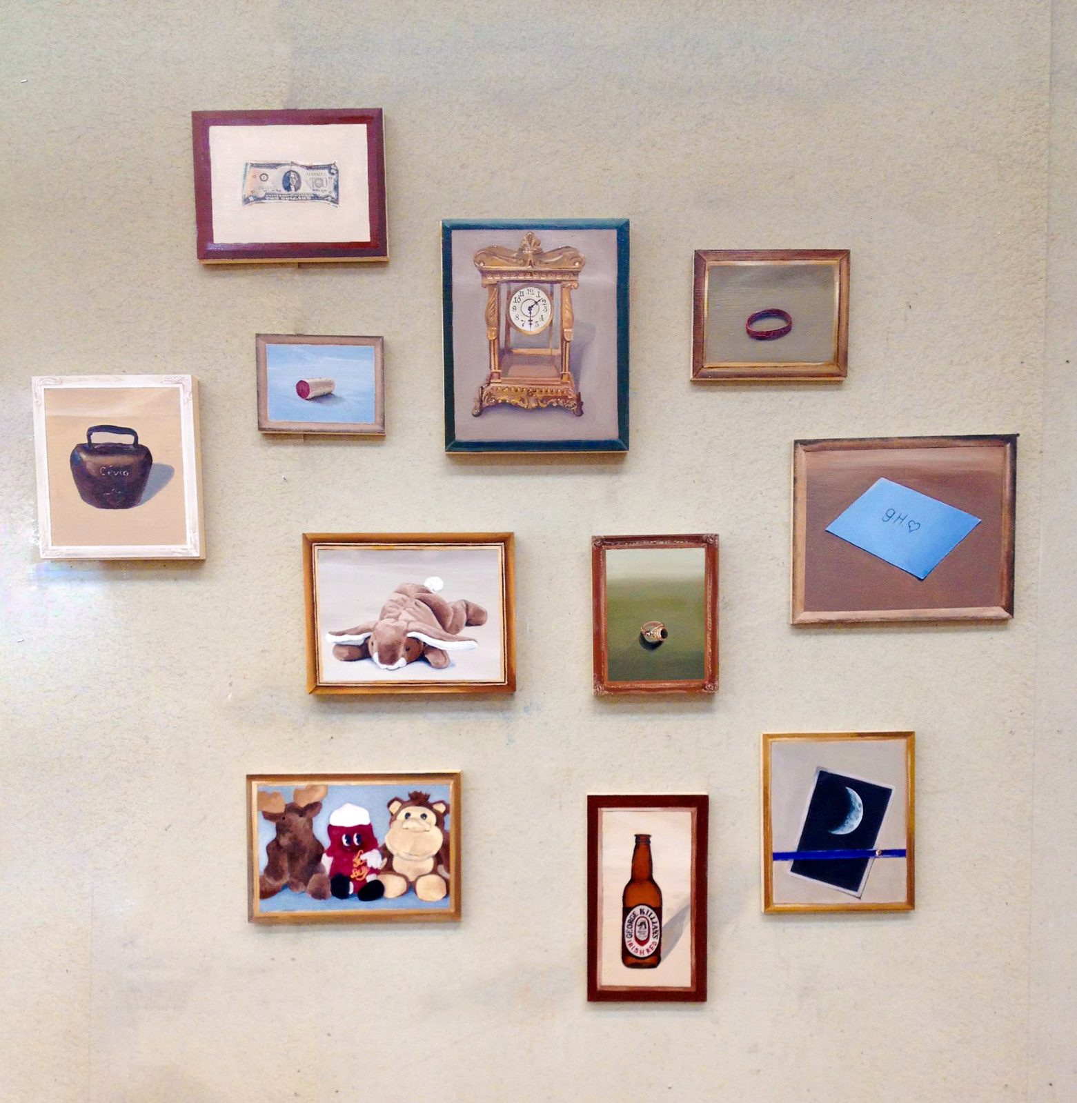 Wall grid of small framed paintings depicting everyday objects, including a clock, ring, toys, and a bottle.