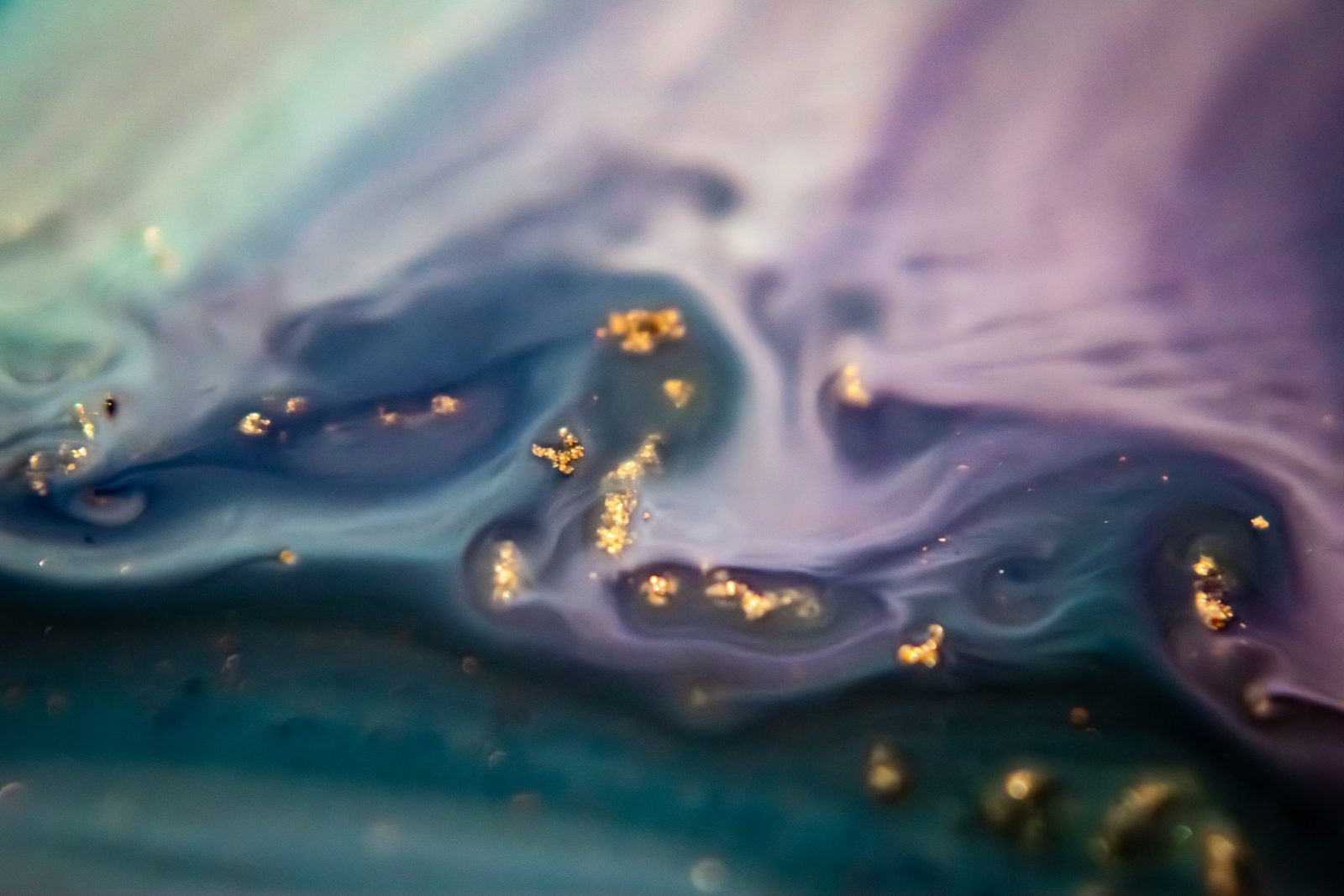 Violet and teal marbled swirl with a dense cluster of gold flecks at centre.
