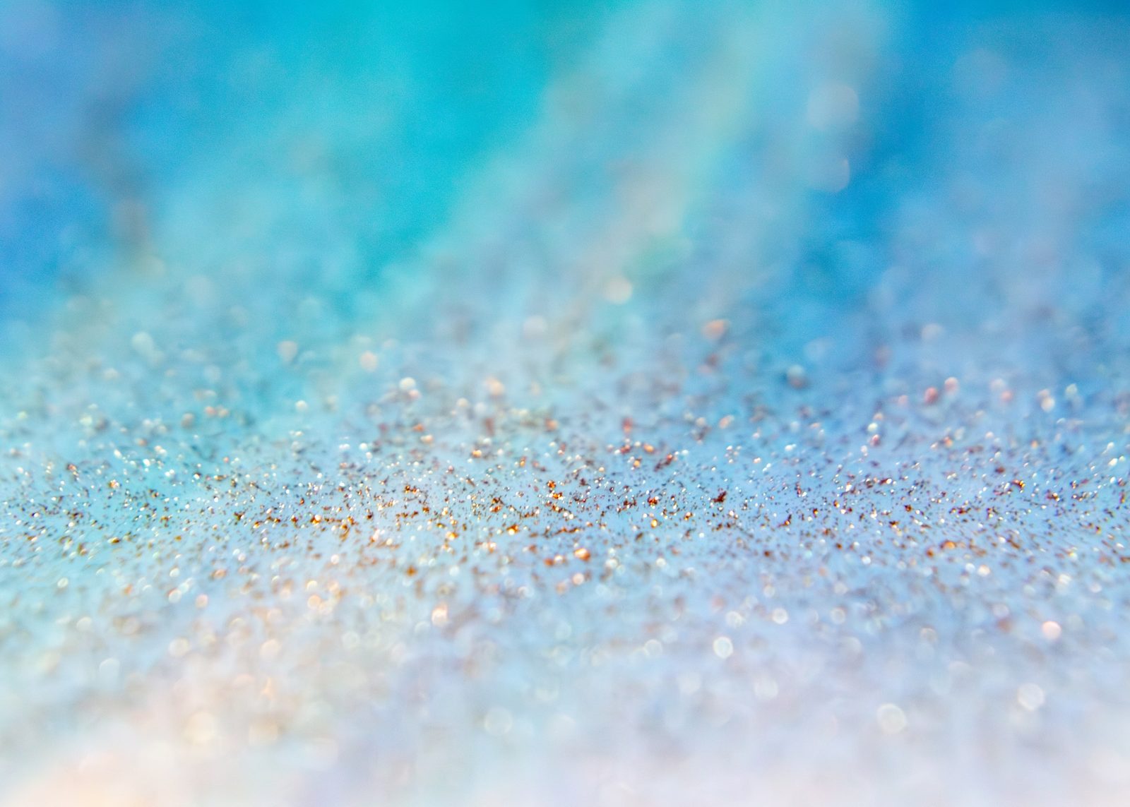 Fine gold and silver glitter scattered across a teal-blue diagonal gradient.