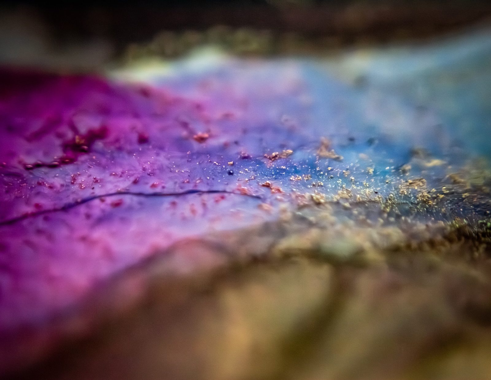 Magenta and slate-blue tones divided diagonally, flecked with gold particles.
