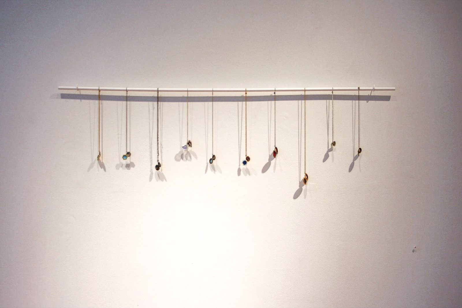 Row of open lockets on chains hanging from a wall-mounted bar.