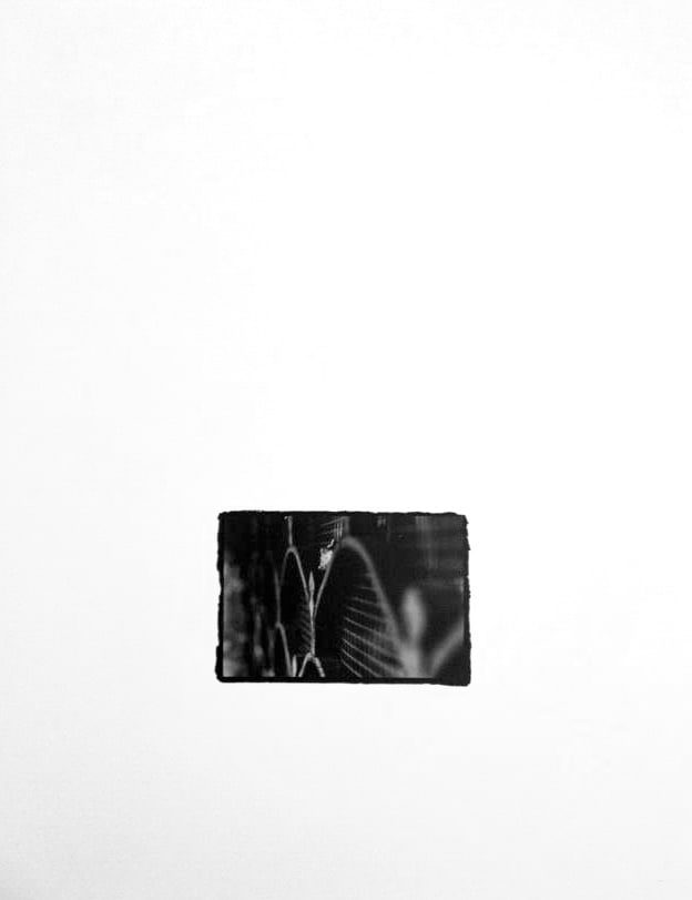 Small black-and-white print, rough-edged on a white ground, showing an iron wall with ornate, radiating patterned ironwork.