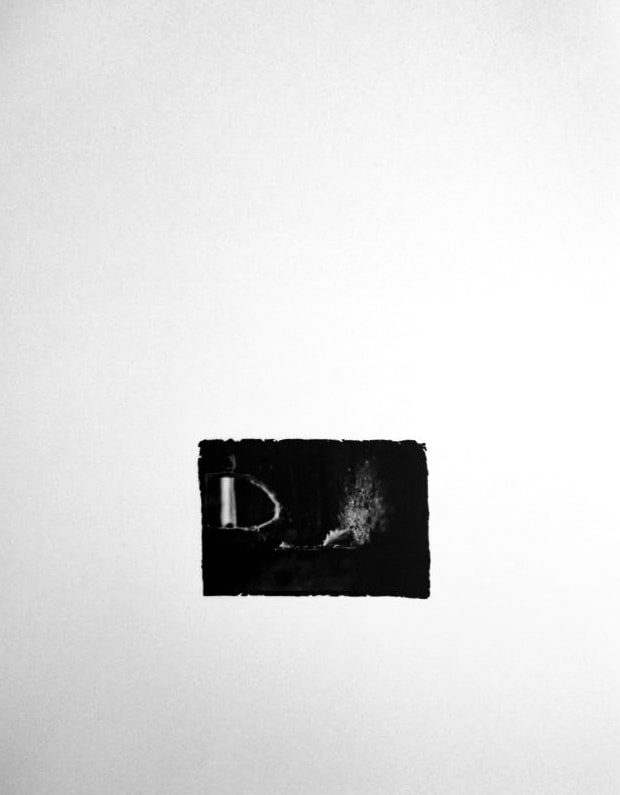 Small black-and-white print, rough-edged on a white ground, showing a pale feather resting in a small dark alcove left by a missing brick.